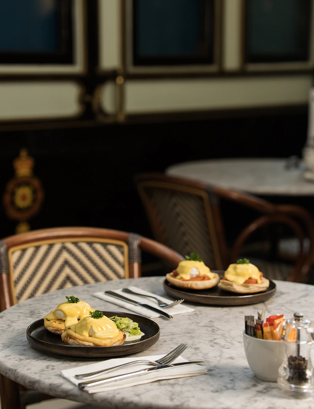 Plates of Eggs Benedict on a marble cafe table.