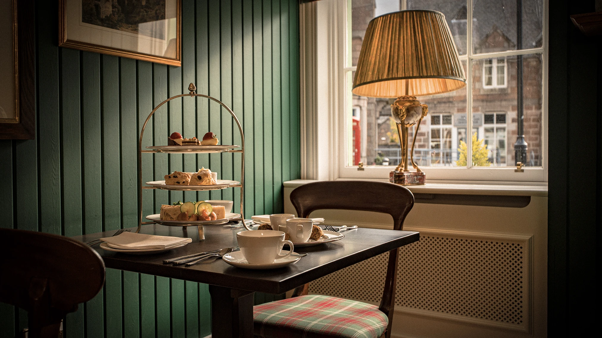 Afternoon tea setup with pastries and cups by a window.