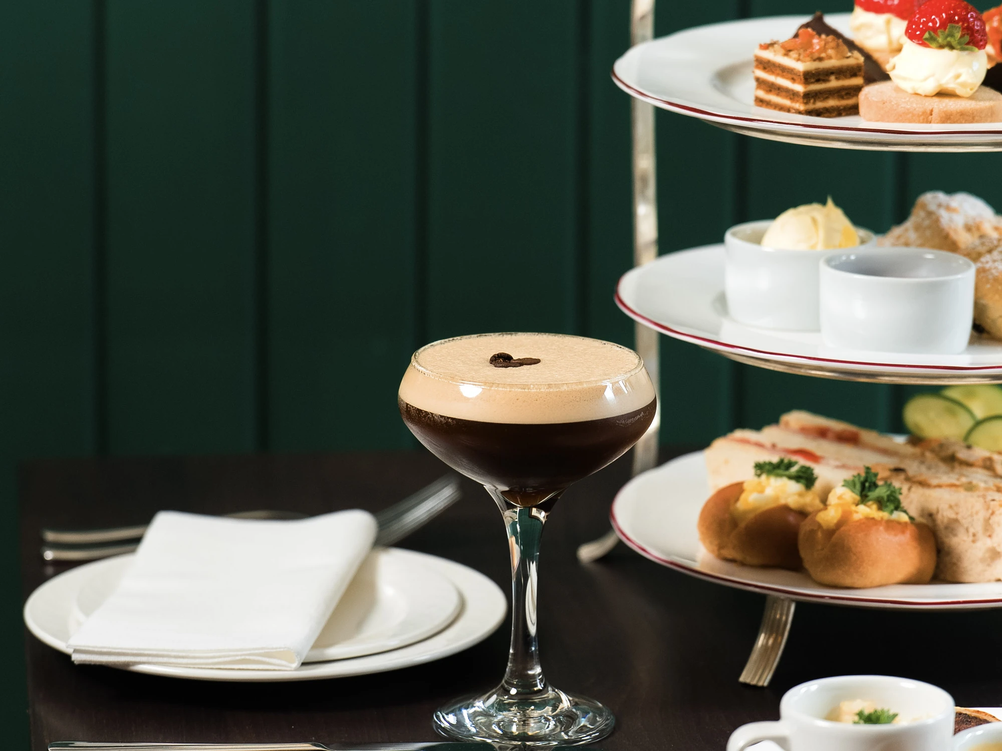 Espresso martini next to a tiered afternoon tea stand.
